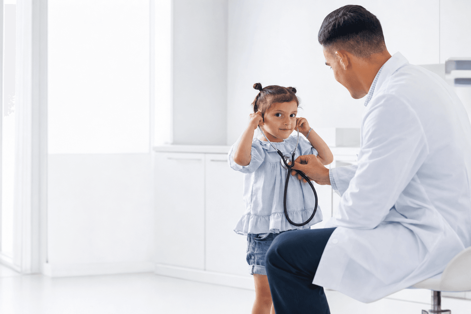 Young girl listening with a stethoscope during a paediatric clinic visit